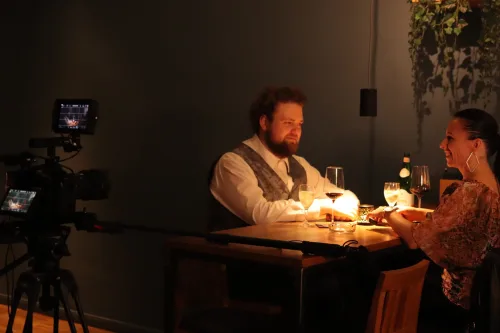 Behind-the-Scenes-Aufnahme eines Filmdrehs in einem Restaurant, Crewmitglieder und Schauspieler bereiten eine Szene vor.